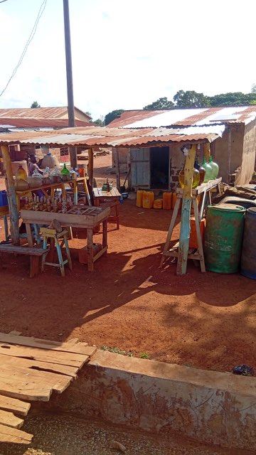 Vue du marché : bouteilles et bidons d’essence devant les étals.