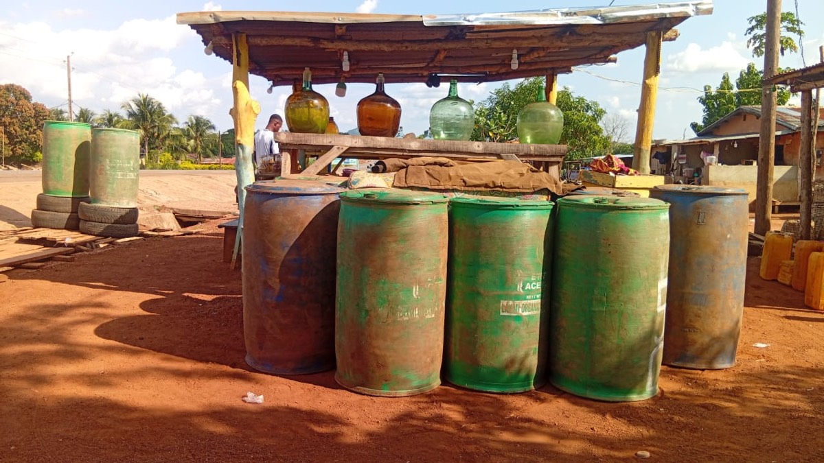 Point de vente d’essence Gloire à Dieu à Gouka : bonbonnes en verre et fûts au bord de la route.
